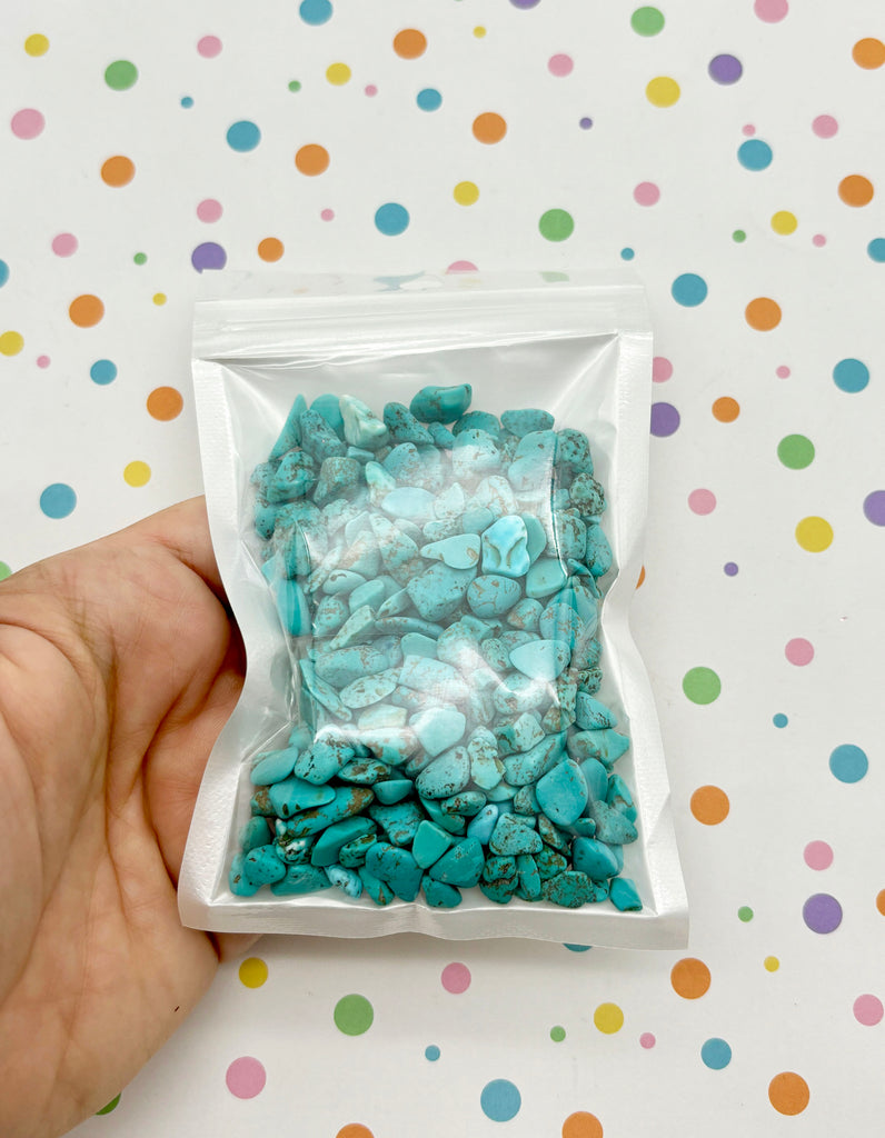 a hand holding a bag of blue rocks