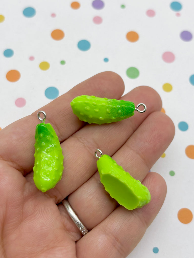 A hand holding three green, spiky pears against a background with colorful polka dots.
