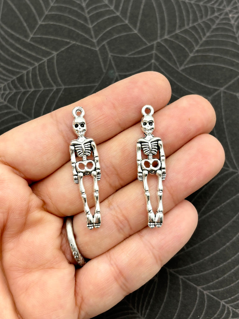 a person holding a pair of skeleton earrings