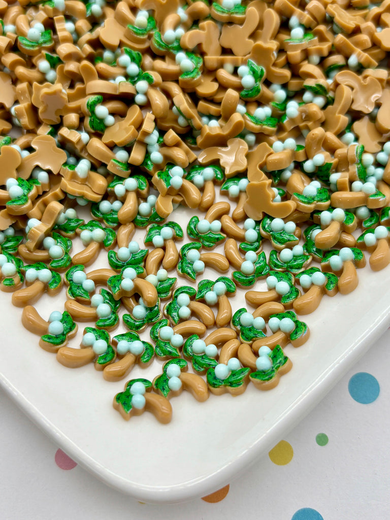 a white plate filled with a variety of colorful candy pieces, including green and brown shapes, scattered across the plate.