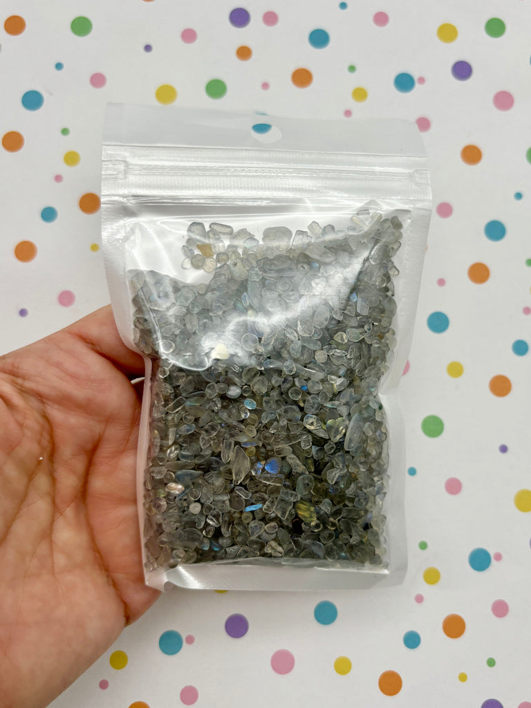 a hand holding a bag of silver flakes