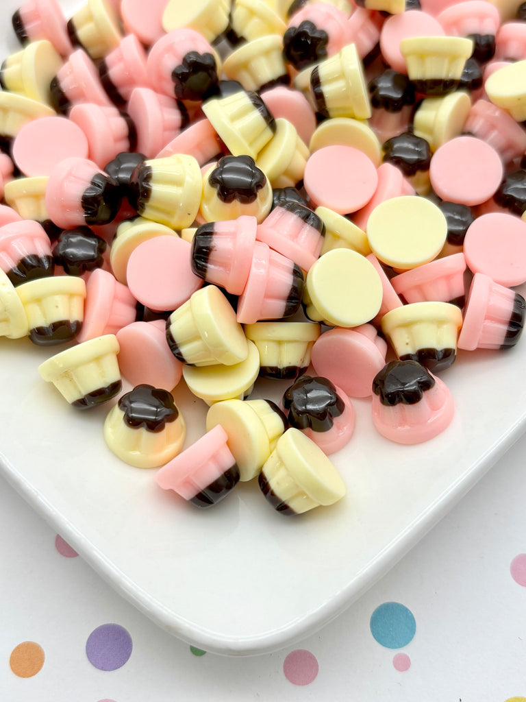 A white plate filled with colorful, round candies in various pastel shades, including pink, yellow, and black.