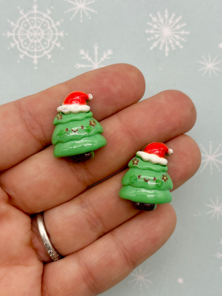 a hand holding a pair of green christmas trees