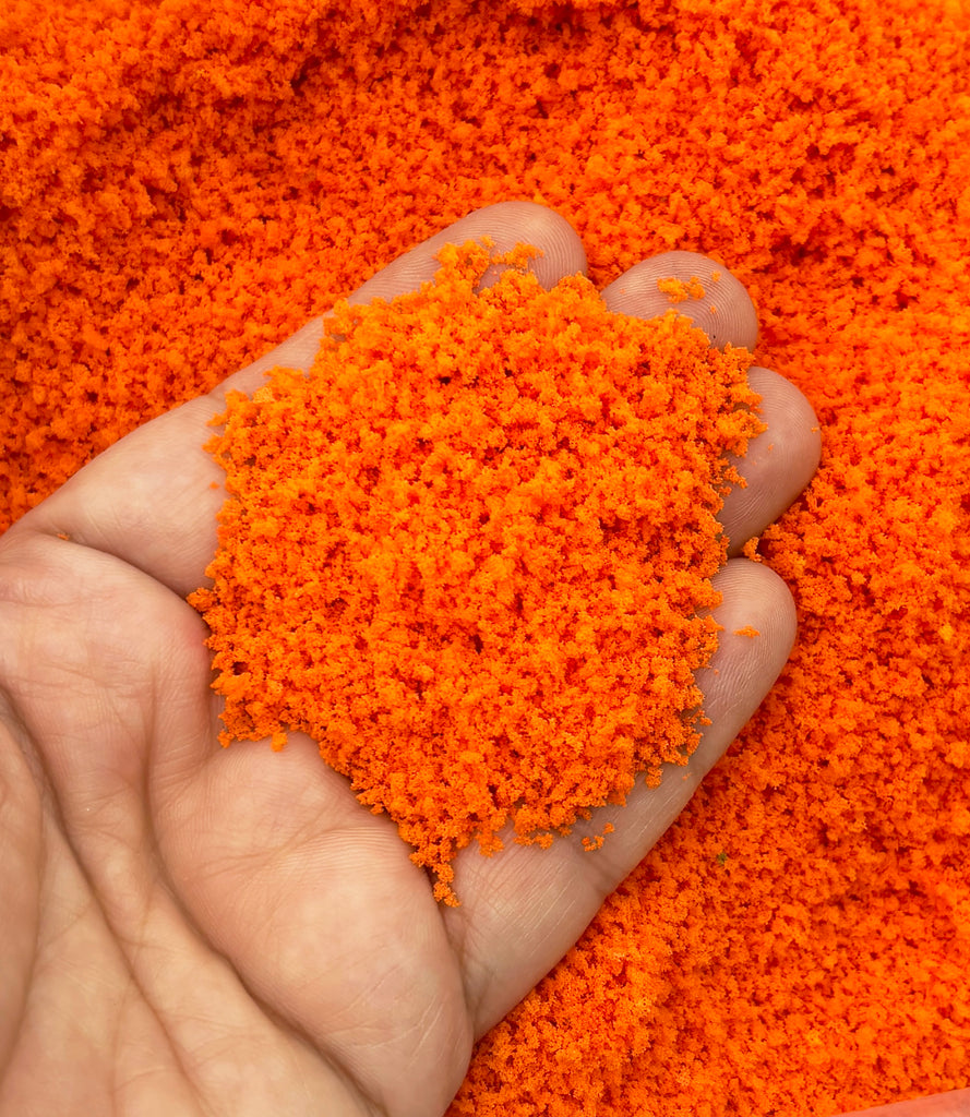 a hand holding a pile of orange colored powder