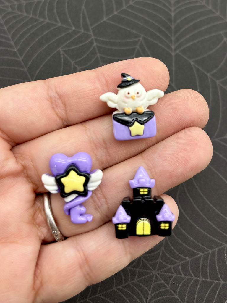 A hand holding three small, colorful plastic objects against a dark background.