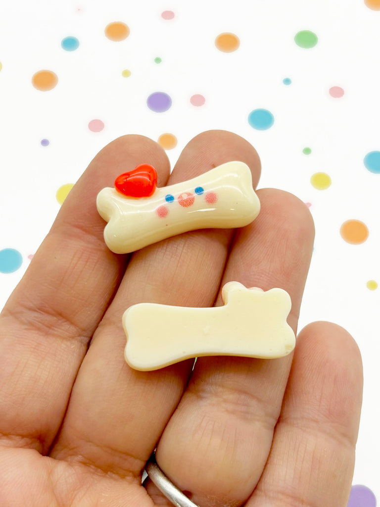 a hand holding a small white dog bone and a red heart