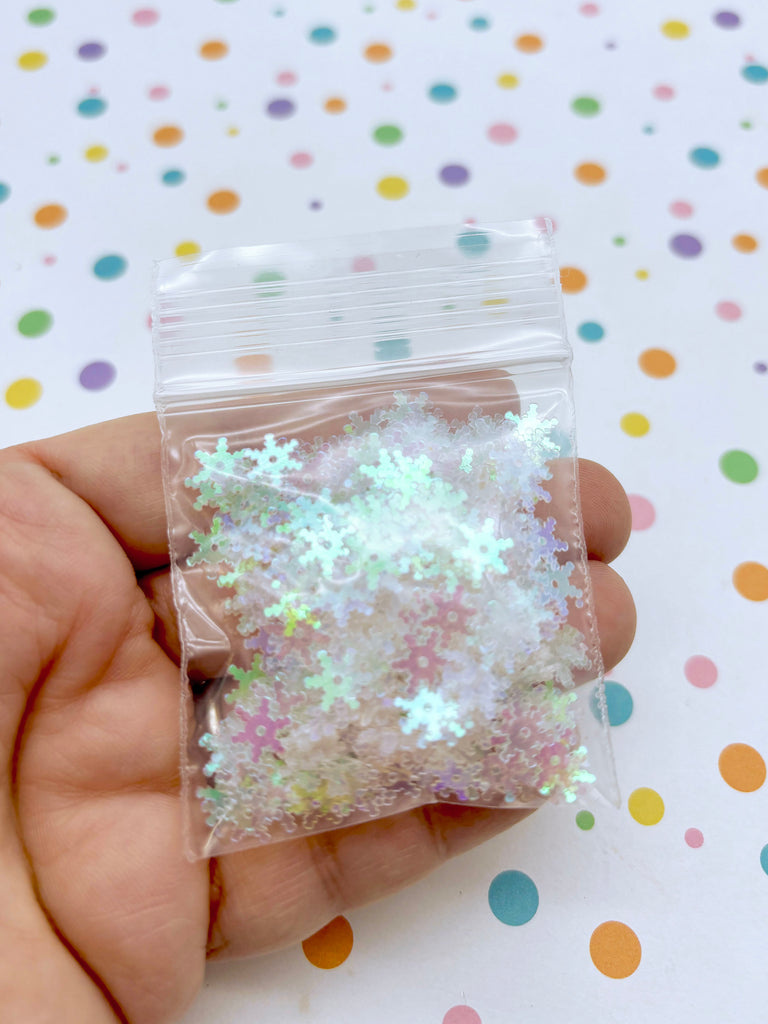 a hand holding a bag of white and green glitter