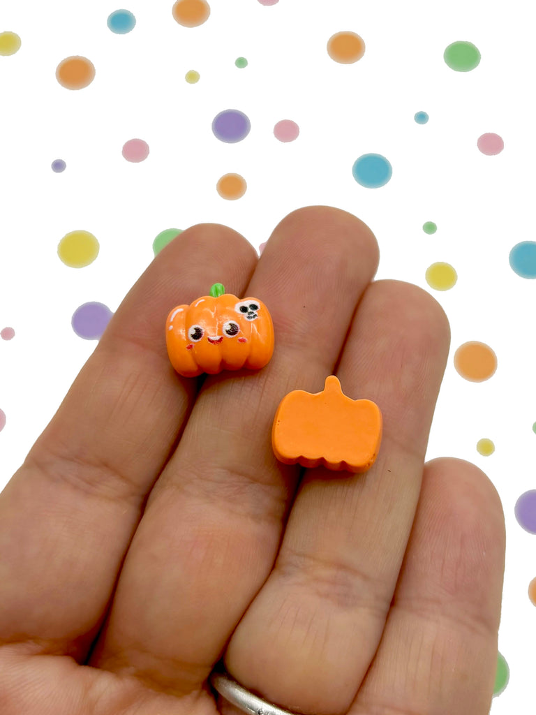 a hand holding a tiny orange pumpkin and a smaller orange pumpkin