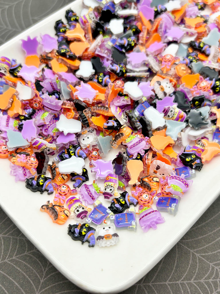 A white plate filled with a variety of colorful, small plastic objects, including black and orange shapes, purple and white shapes, and other Halloween-themed decorations.