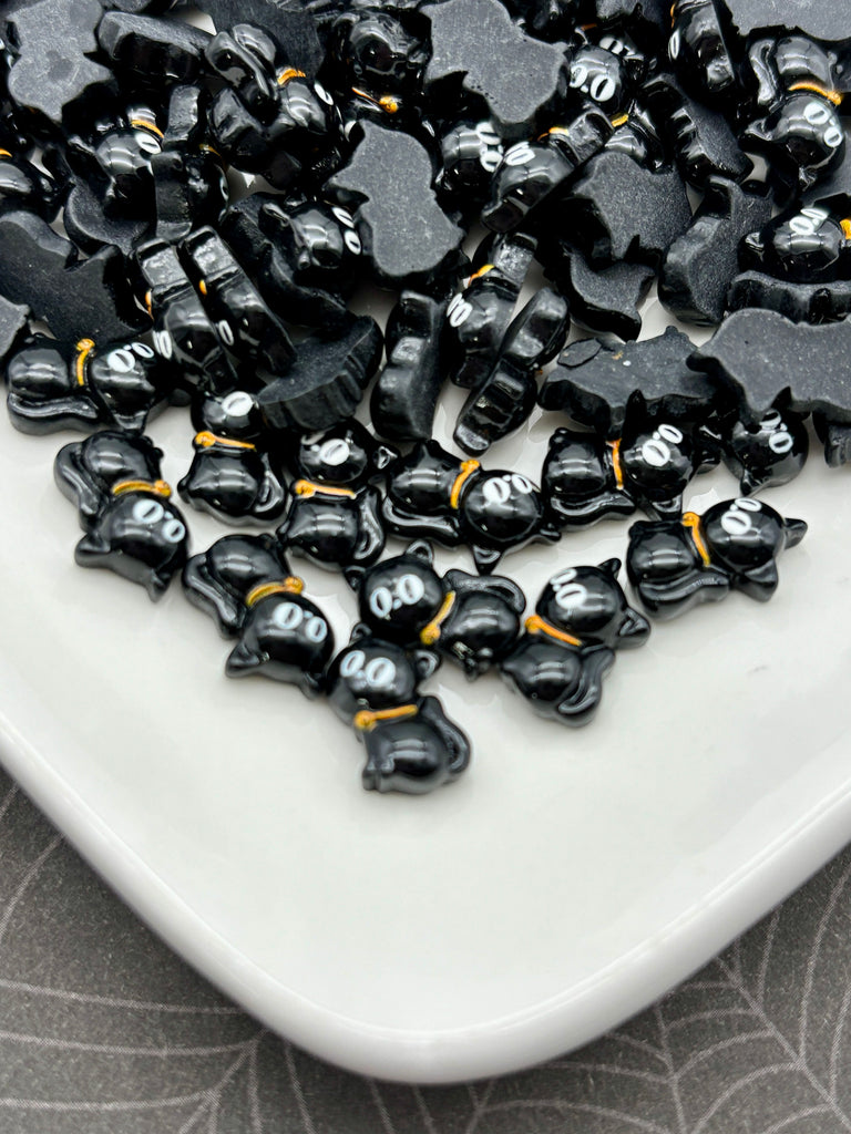 a white plate with a collection of black cat-shaped beads or charms scattered across it.