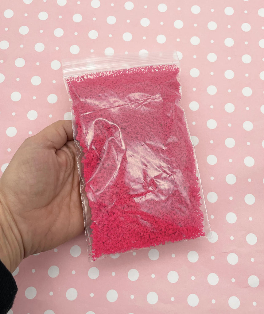 a hand holding a bag of pink powder