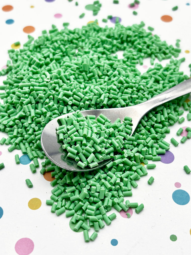 a spoon full of green sprinkles on a table