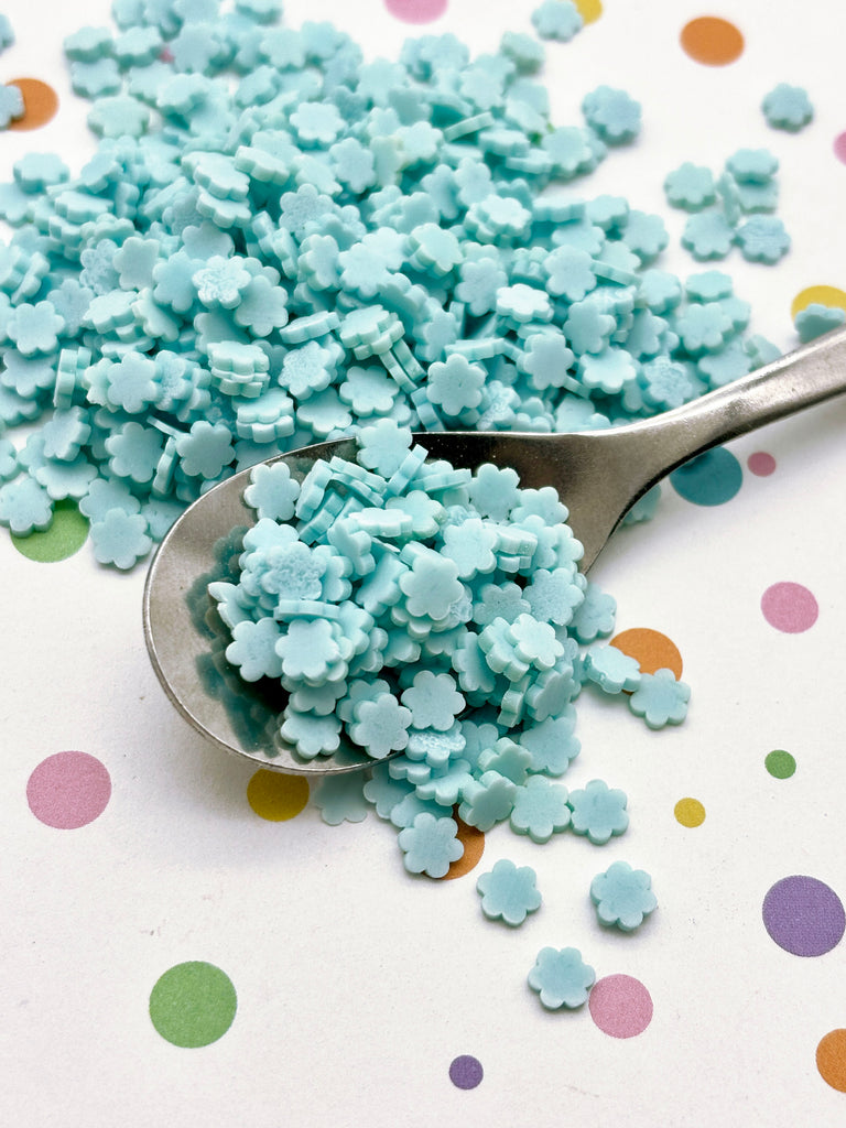 a spoon full of blue sprinkles on a polka dot tablecloth