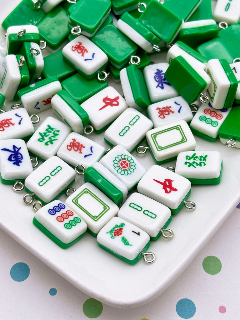 a collection of green and white mahjong tiles arranged on a white surface, with some of the tiles featuring colorful designs.