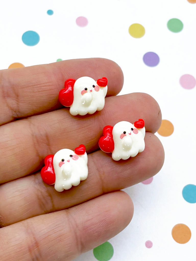 a hand holding two small red and white teddy bears