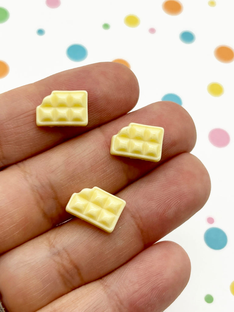 a hand holding two small pieces of yellow chocolate