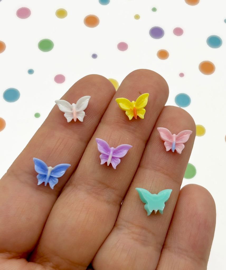 a person's hand holding four small butterflies