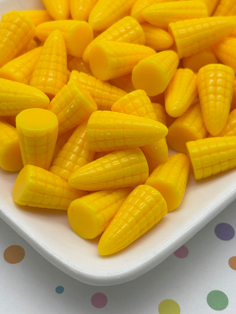 A white plate filled with yellow plastic corn kernels, arranged in a visually appealing manner.