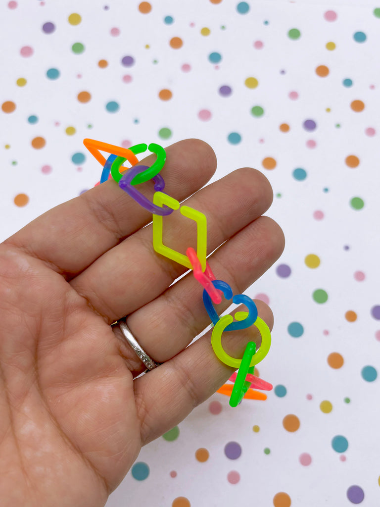 A hand holding a colorful plastic bracelet against a background of multicolored polka dots.