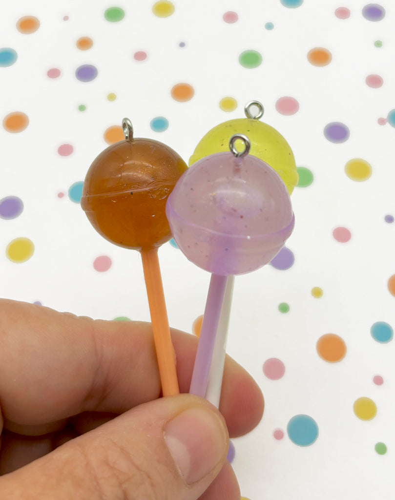 a person holding two lollipops in their hand