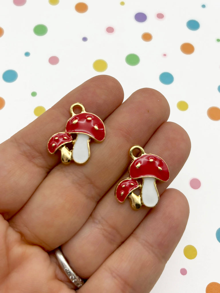 a hand holding a pair of red and white mushrooms