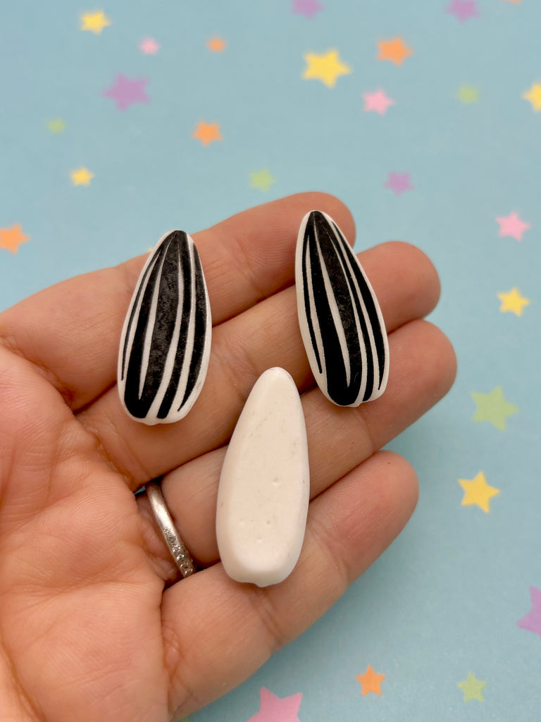 a hand holding two small white and black pins