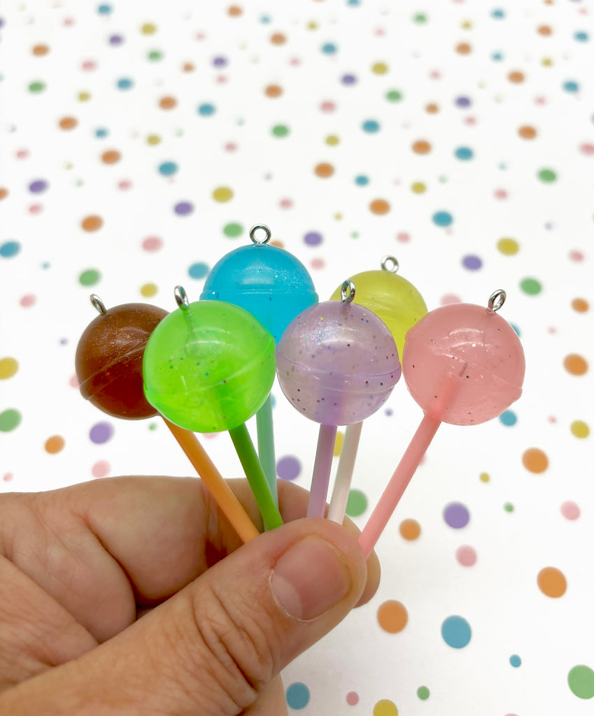 a hand is holding four lollipops on a stick