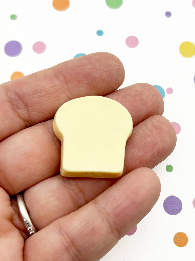 A hand holding a small, yellow object against a background with colorful polka dots.