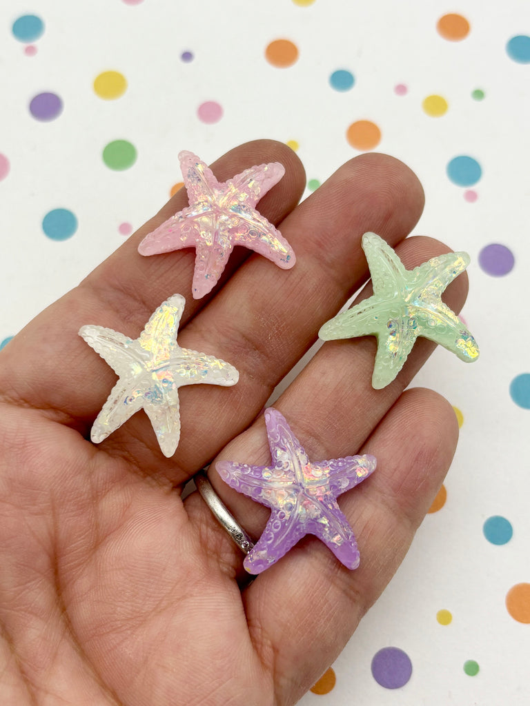 A hand holding four colorful starfish-shaped objects against a background with polka dots.