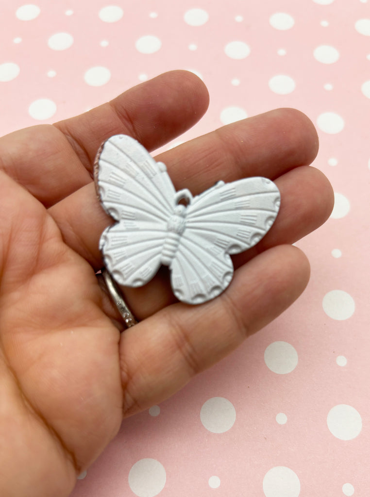 a hand holding a small white butterfly brooch