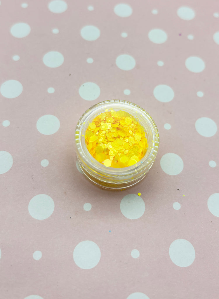 a small jar of yellow glitter sitting on a polka dot tablecloth