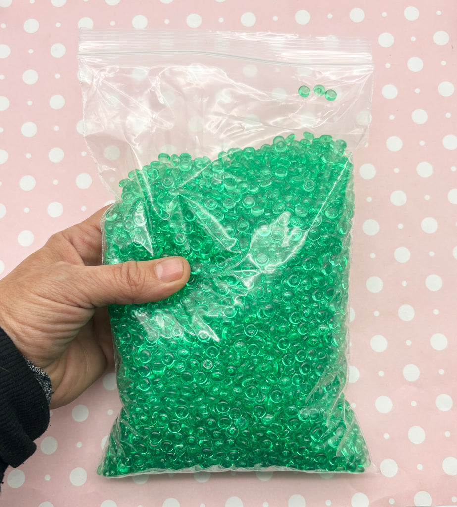 a hand holding a bag of green beads