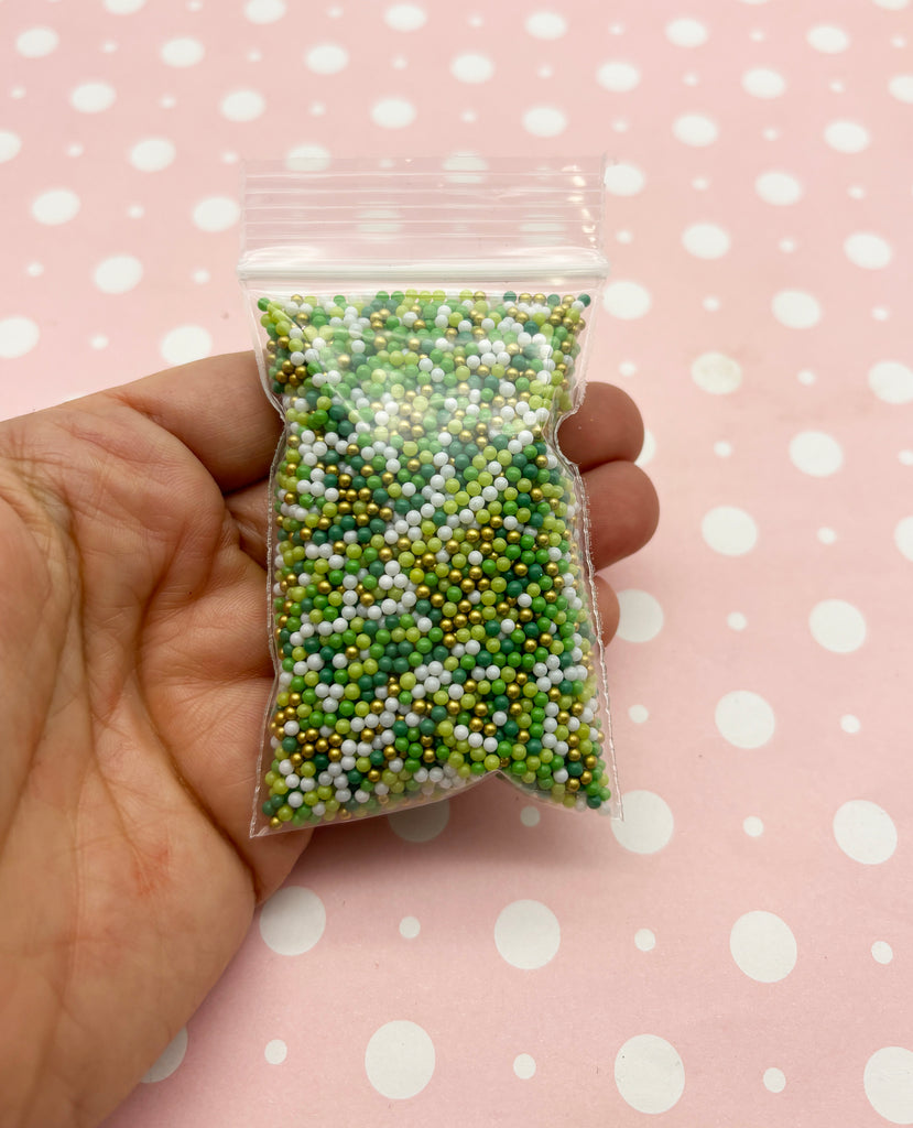 a hand holding a bag of green and white beads