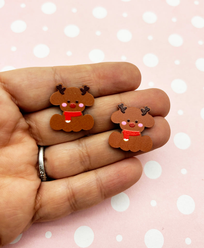 a hand holding a pair of reindeer earrings