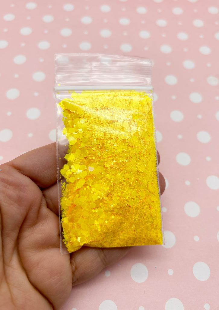 a hand holding a bag of yellow glitter