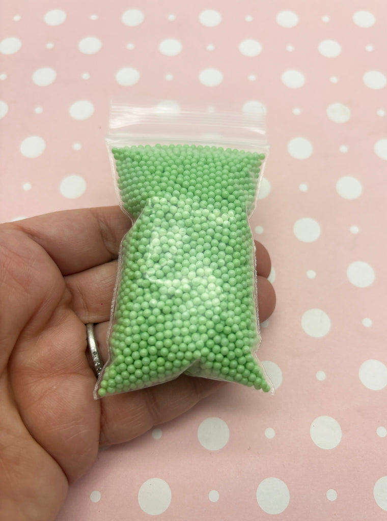 a hand holding a bag of green beads