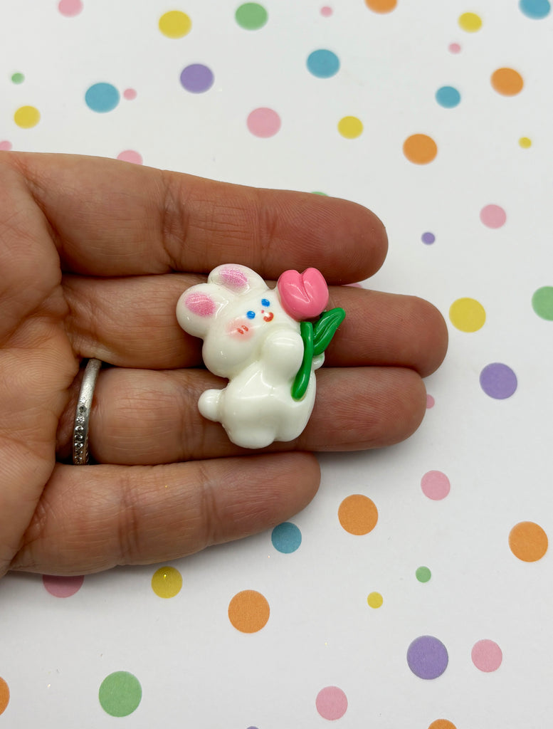a person holding a small white toy animal in their hand