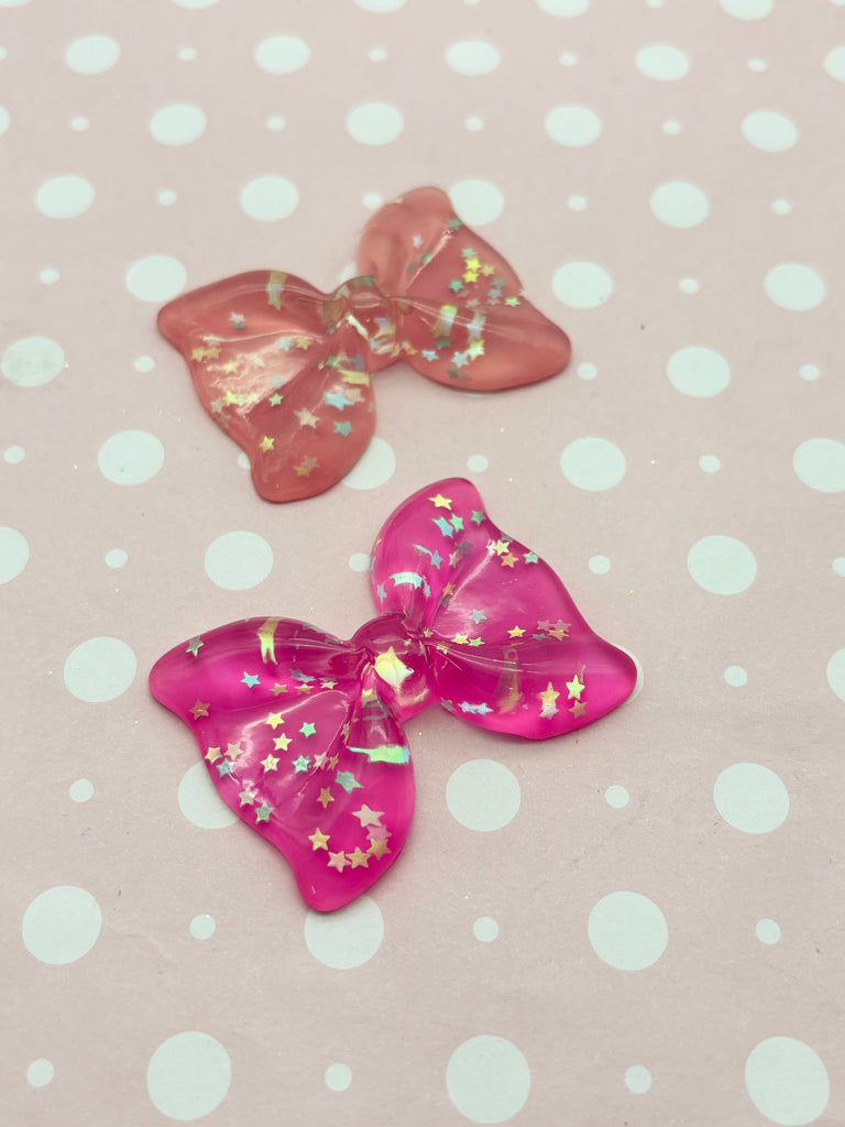two pink bows with gold stars on a polka dot background