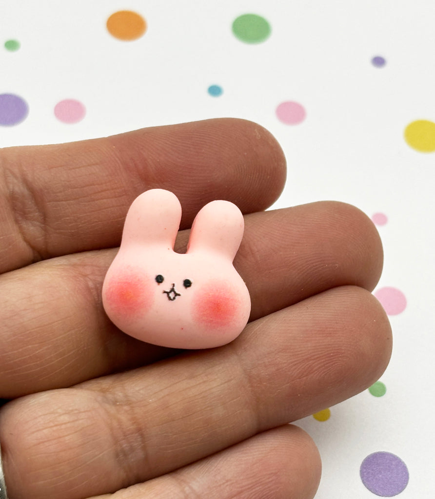 a hand holding a tiny pink toy rabbit