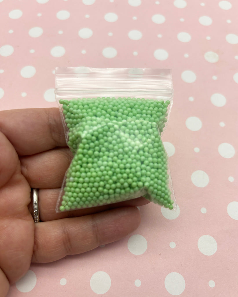 a hand holding a bag of green beads