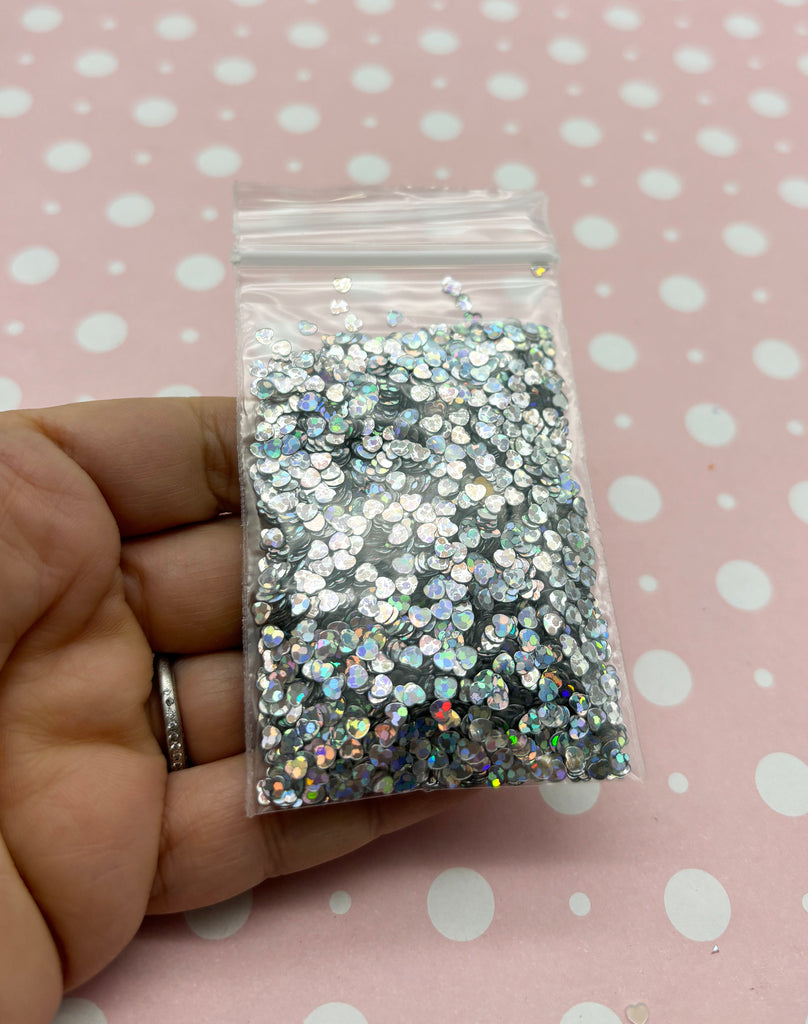 a hand holding a bag of silver glitter