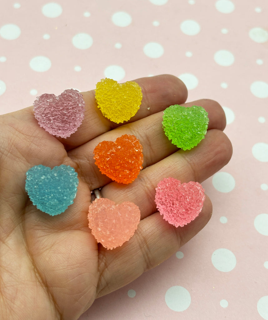 a hand holding five small heart shaped candies