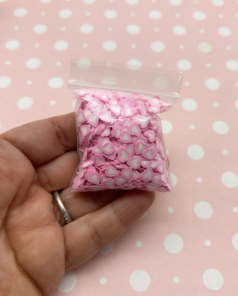 a hand holding a bag of pink and white flowers