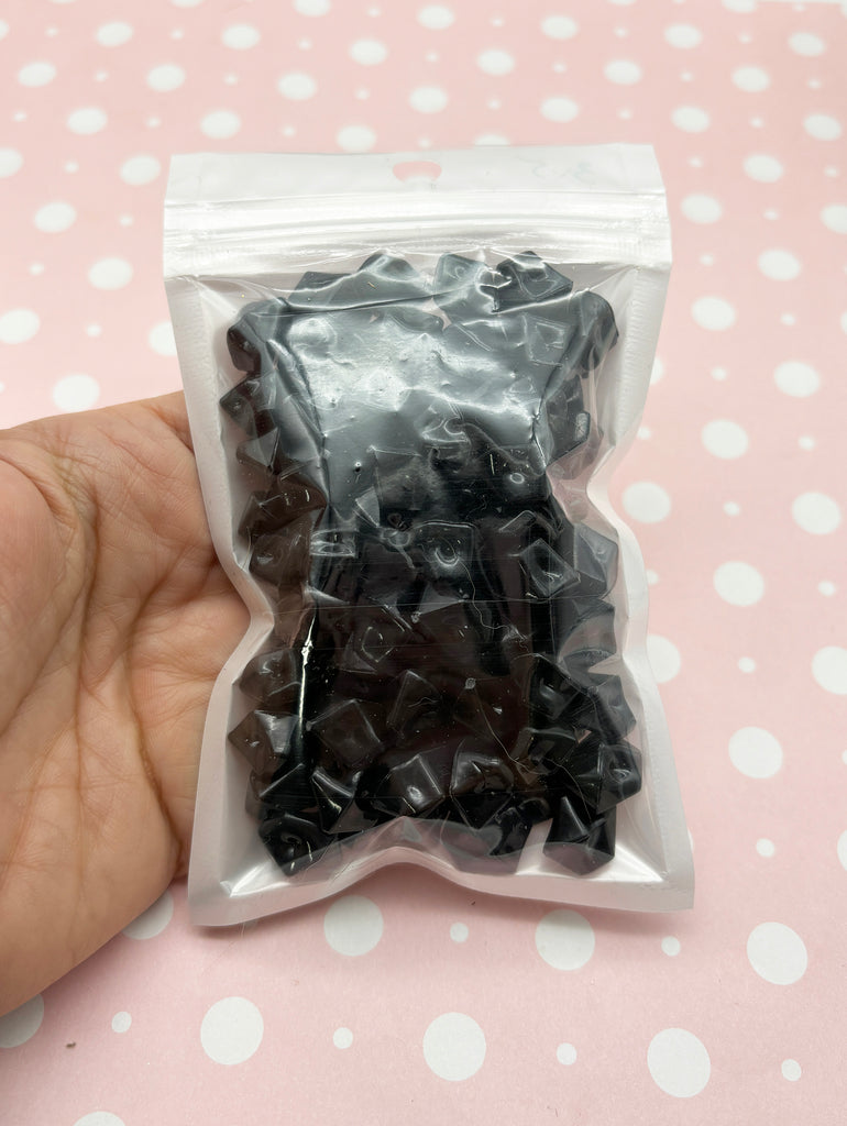 a hand holding a bag of black and white candies