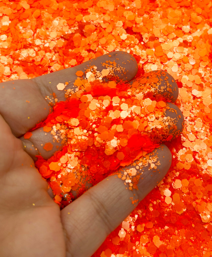 a hand holding a handful of orange glitter