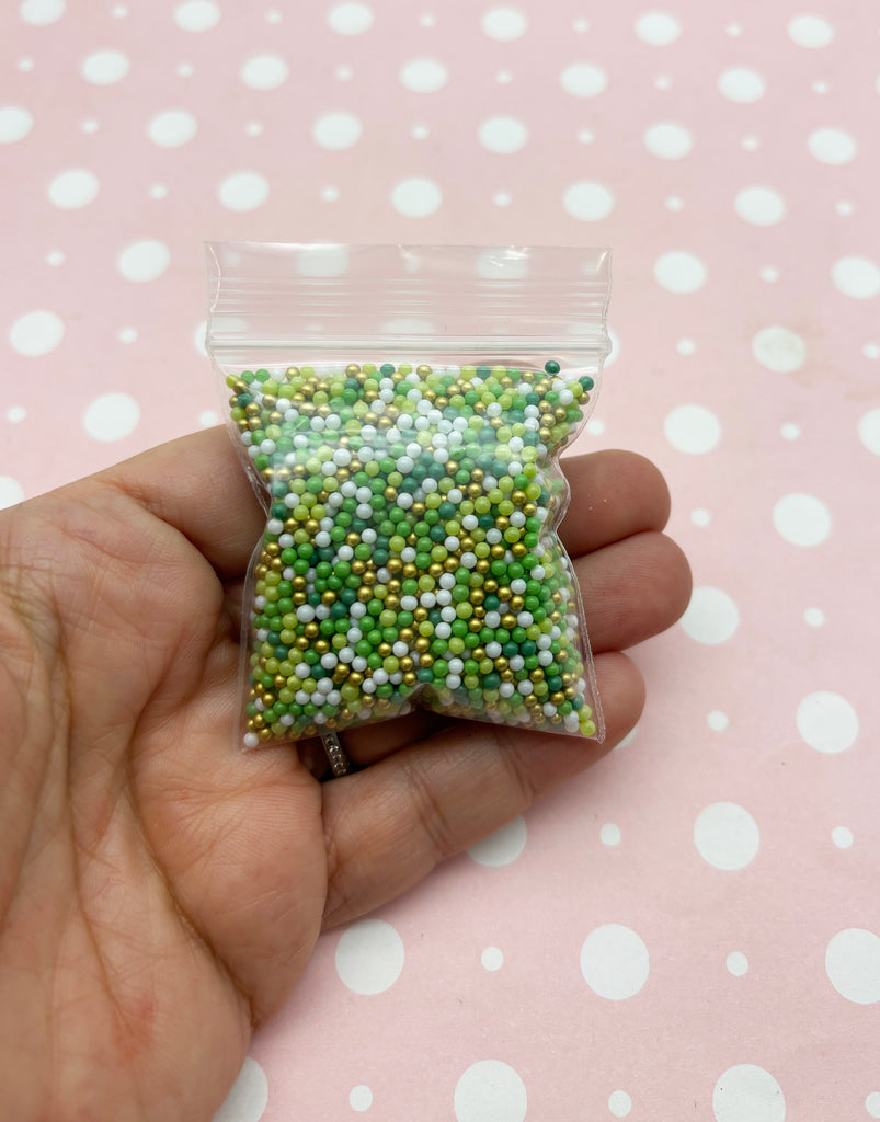 a hand holding a bag of green and white beads