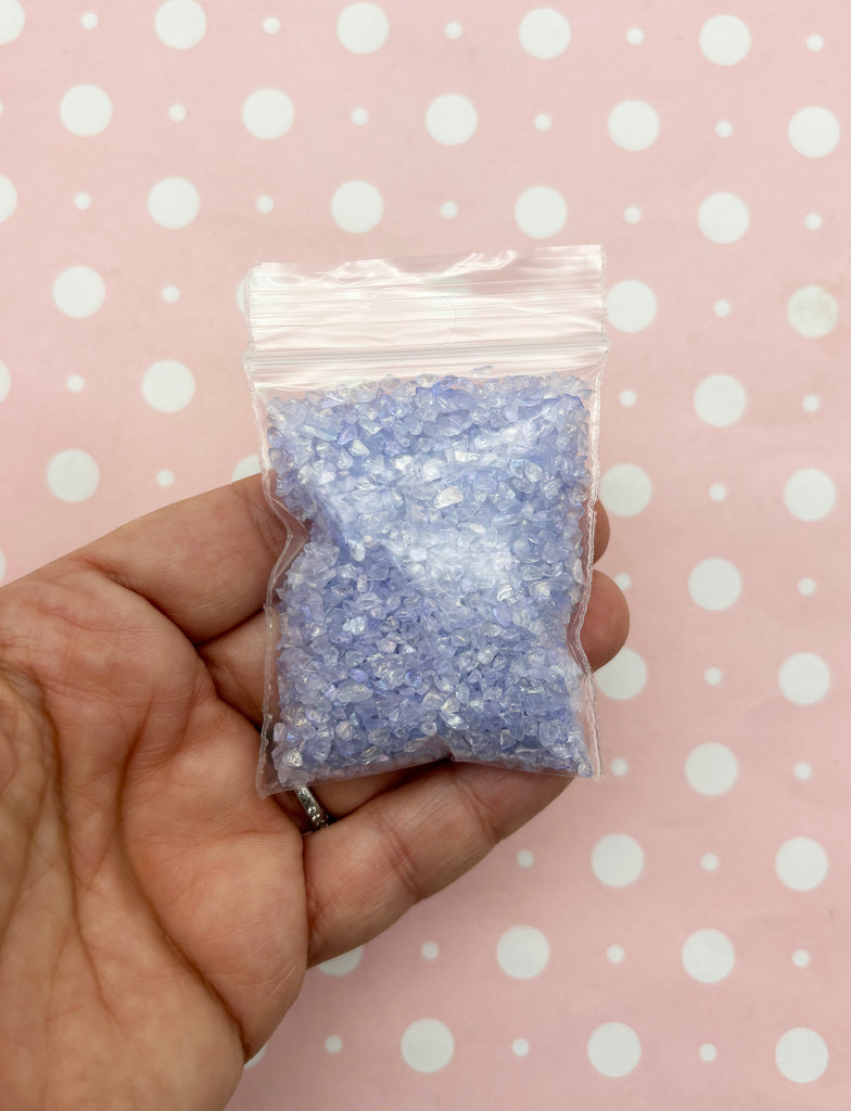 a hand holding a bag of blue glitter