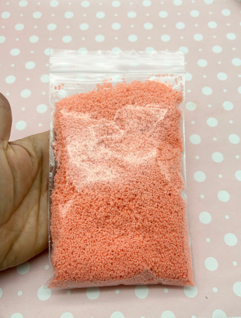 a hand holding a bag of pink powder