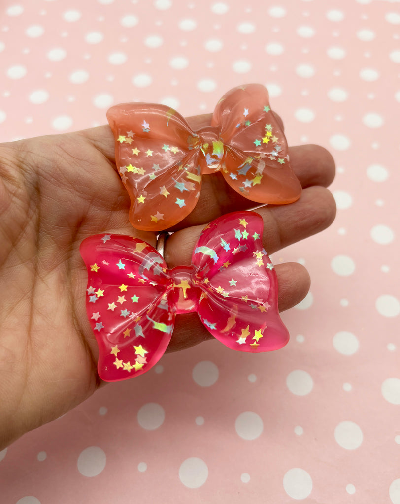 a hand holding two small bows with stars on them