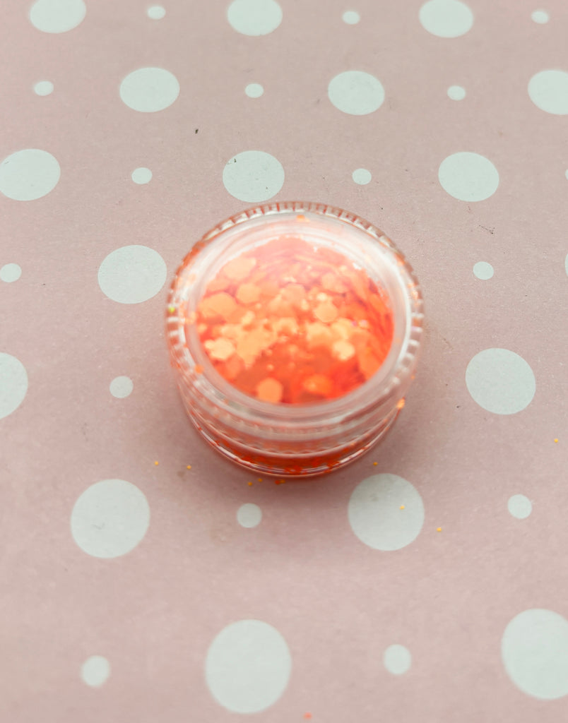 a small jar of orange glitter sitting on a polka dot tablecloth